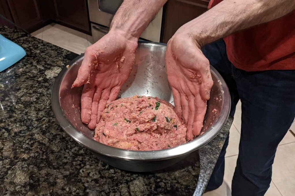 Hand mixing raw ground beef and other ingredients