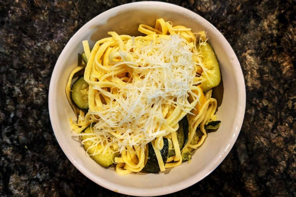 Fusilli Con Buco - bowl of linguini pasta with zucchini, topped with shredded parmesan cheese