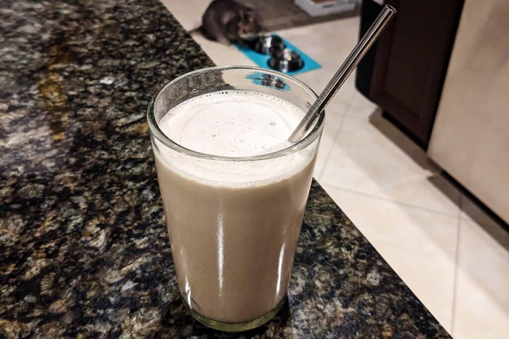 Glass of a black and white malt with a metal straw