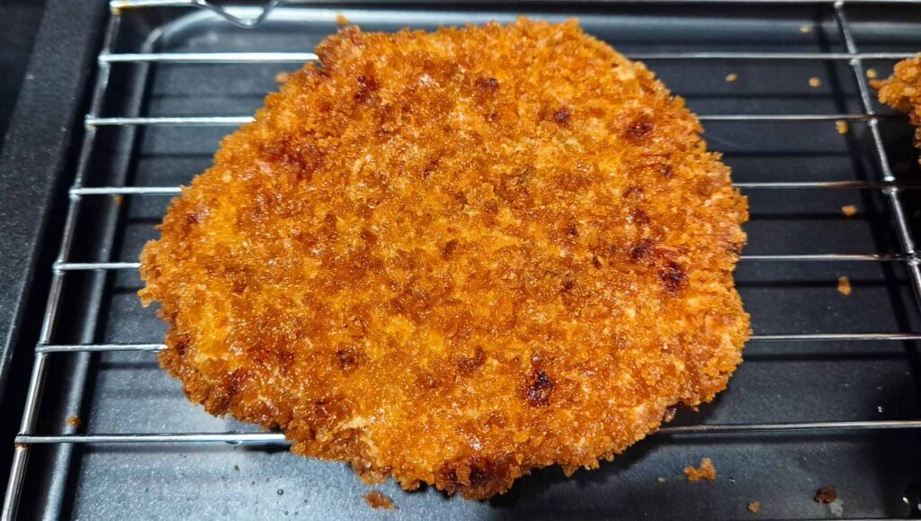Fried pork cutlet Tonkatsu laying on wire cooling rack