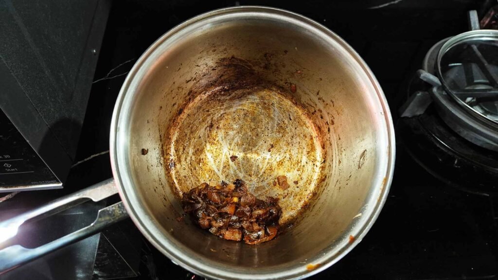 Caramelized onions covered with curry mix in a stainless steel pot