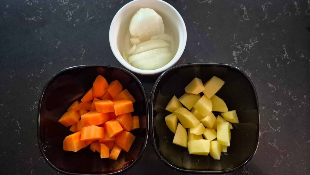 Ingredient bowls of diced carrots, potatoes, and onions